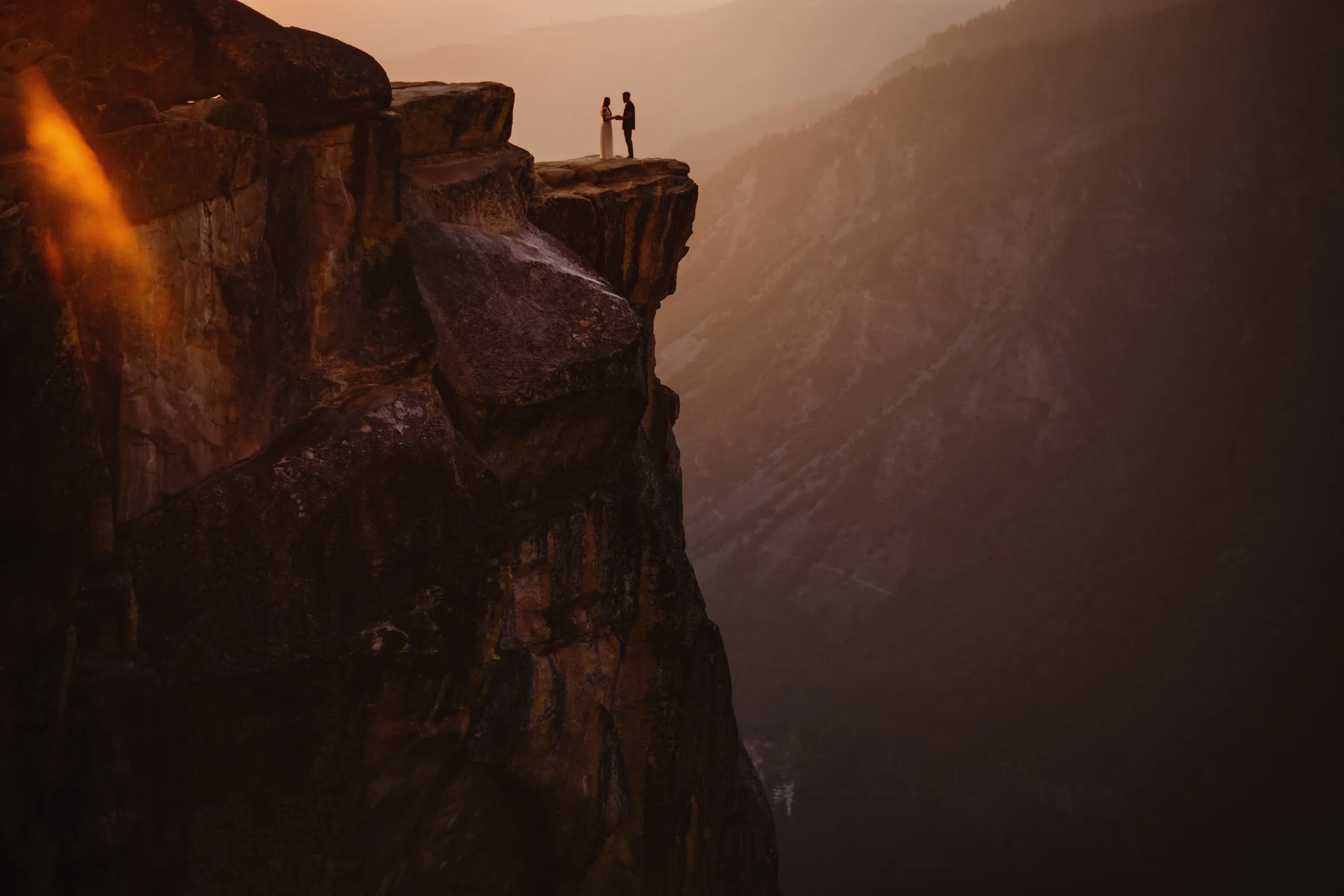 A couple on a cliff edge at sunset, photographed by Gabe McClintock
